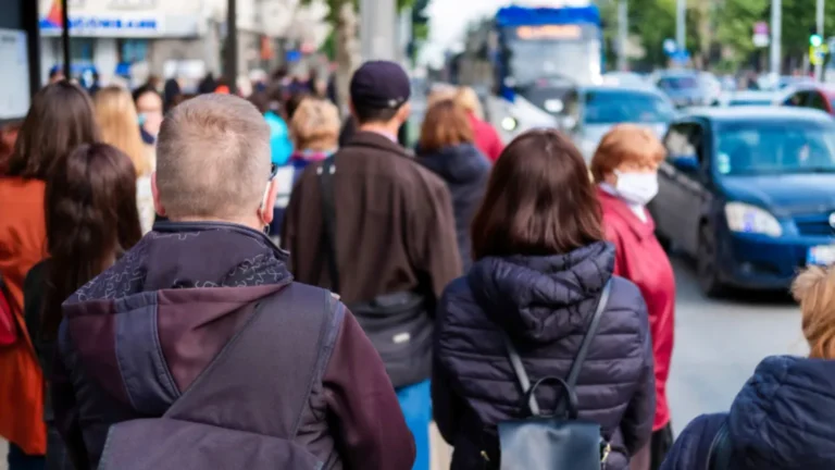 Fotografía de una fila de personas muy prolongada en la parada de autobuses